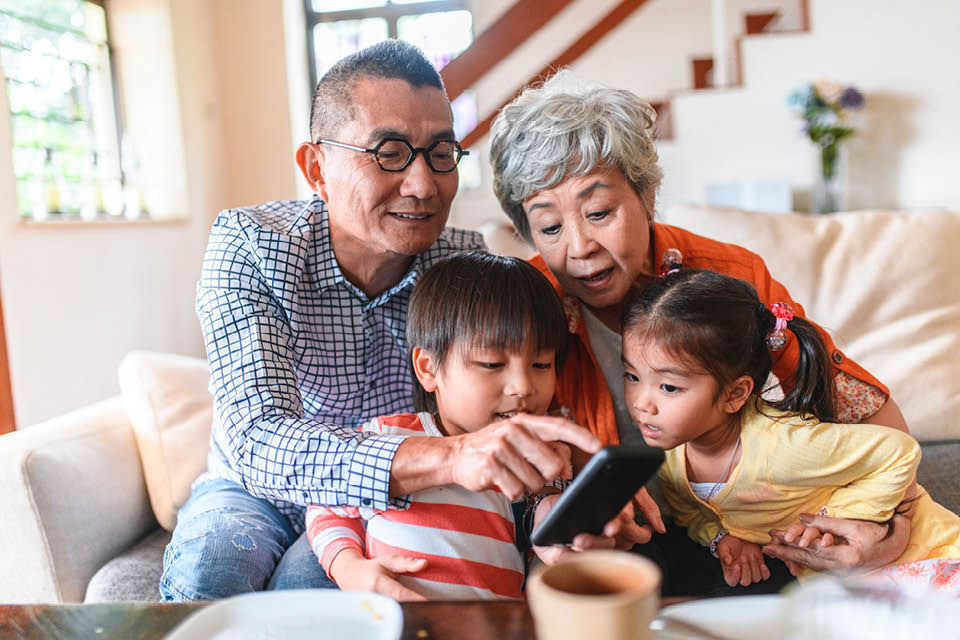 A family huddled together over a mobile phone.