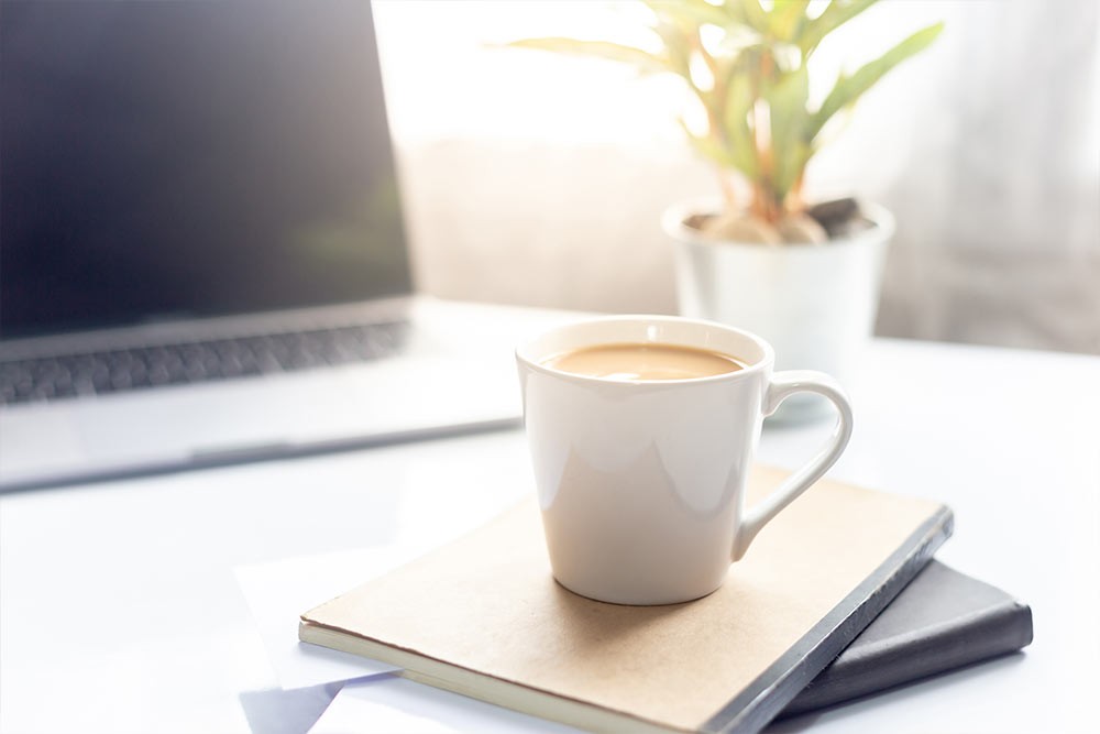 A cup of coffee placed on top of notebooks.