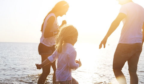 A family of three playing in the ocean.