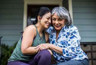 Mother and daughter hugging and smiling on the porch