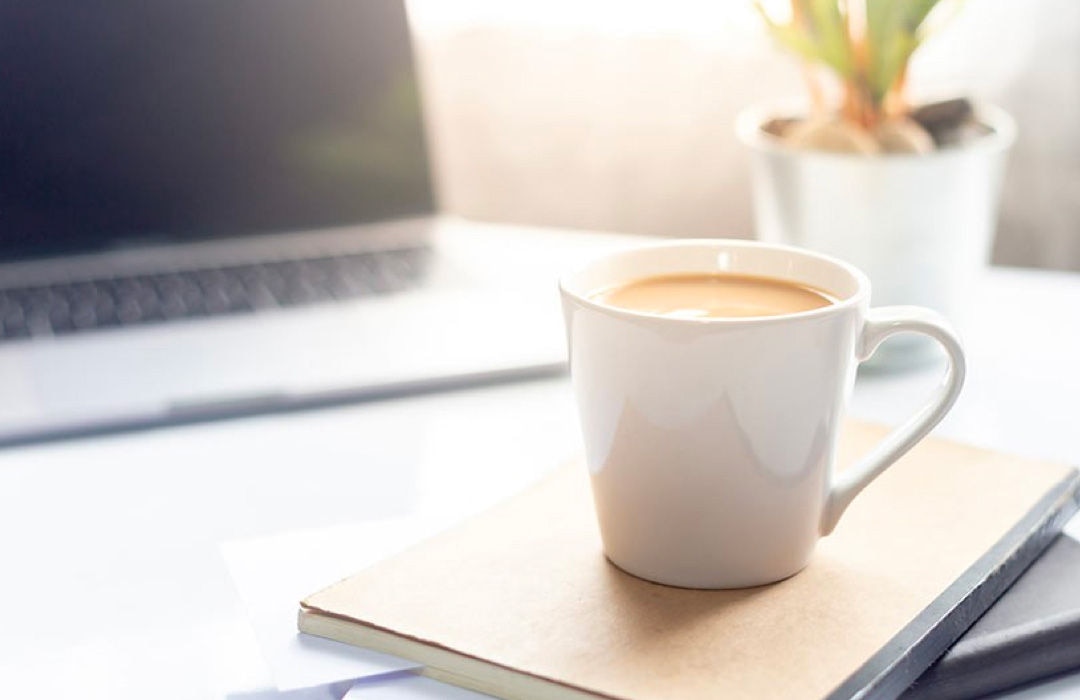 A cup of coffee balanced on top of a notebook.